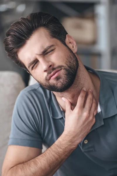 Young man touching his neck — Stockfoto