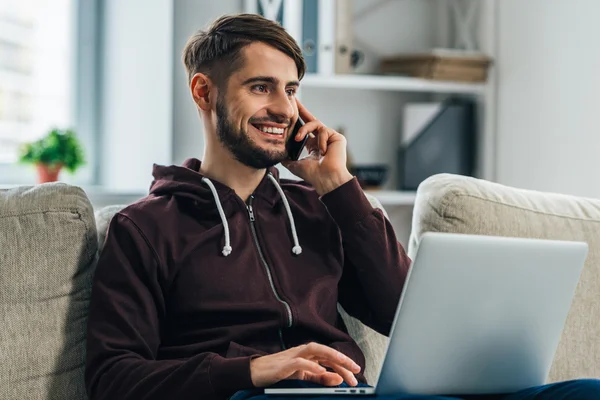 Uomo che utilizza laptop e telefono cellulare — Foto Stock