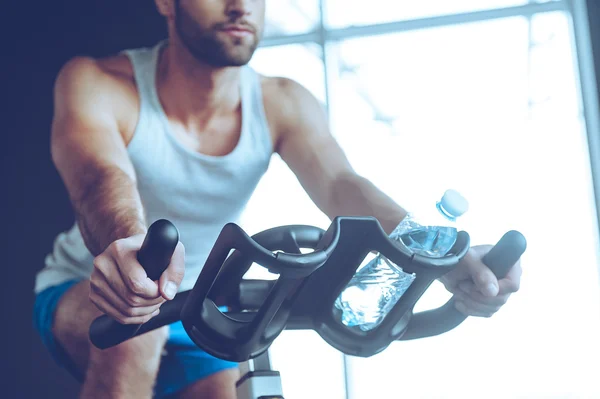 Jongeman fietsen op sportschool — Stockfoto