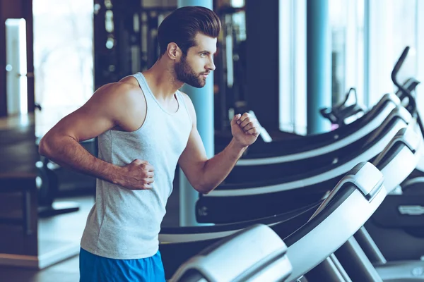 Young man in sportswear running on treadmill — Stock Photo, Image