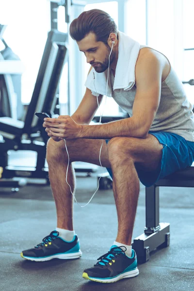 Anak muda dengan headphone dengan telepon di gym — Stok Foto