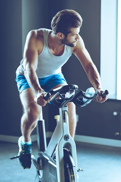 Młody człowiek na rowerze na siłowni — Zdjęcie stockowe