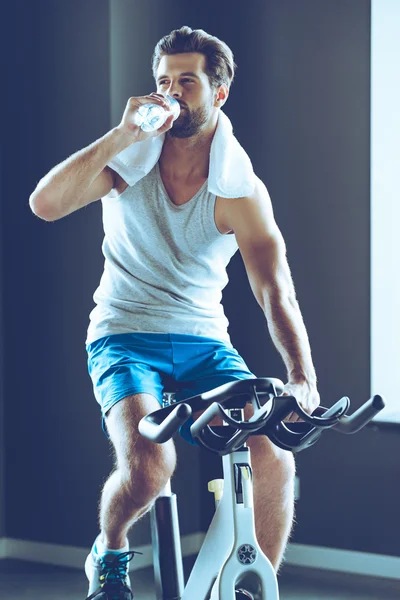 Ung mann som sykler i gymsalen – stockfoto