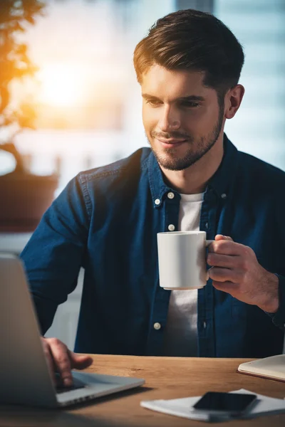 Mann mit Kaffeetasse benutzt Laptop — Stockfoto