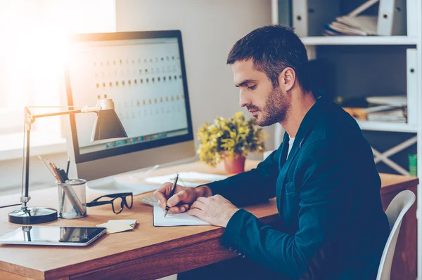 Homem escrevendo algo em seu caderno — Fotografia de Stock