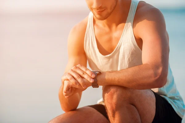 Jovem homem muscular verificando o tempo — Fotografia de Stock