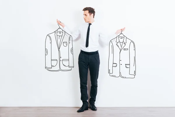 Young man choosing jackets — Stock Photo, Image