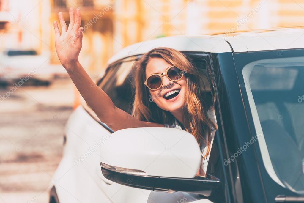 woman waving while sitting in car
