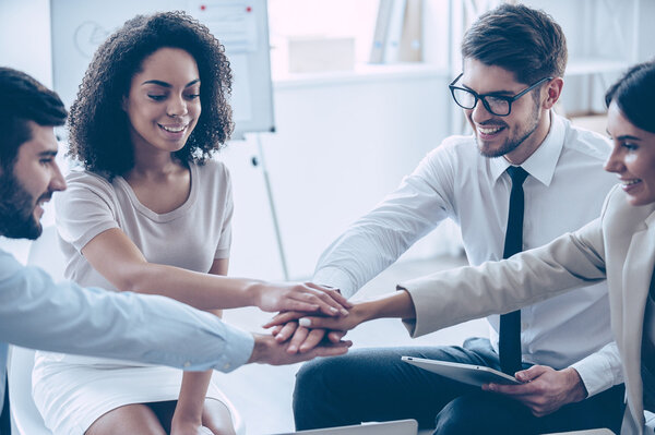 young people holding hands at office 