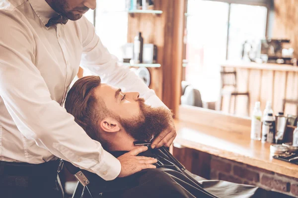 Young bearded man with hairdresser — Stockfoto