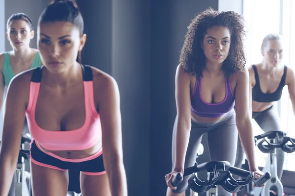 Young beautiful women cycling at gym