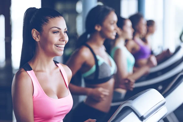 Jeunes belles femmes courant sur tapis roulant à la salle de gym Images De Stock Libres De Droits