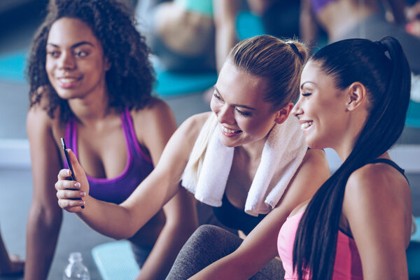 Beautiful young women sitting on exercise mat at gym 