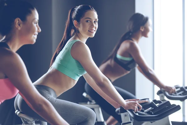 Jeunes belles femmes faisant du vélo au gymnase — Photo