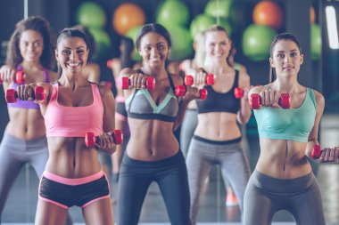 Young beautiful women exercising with dumbbells clipart