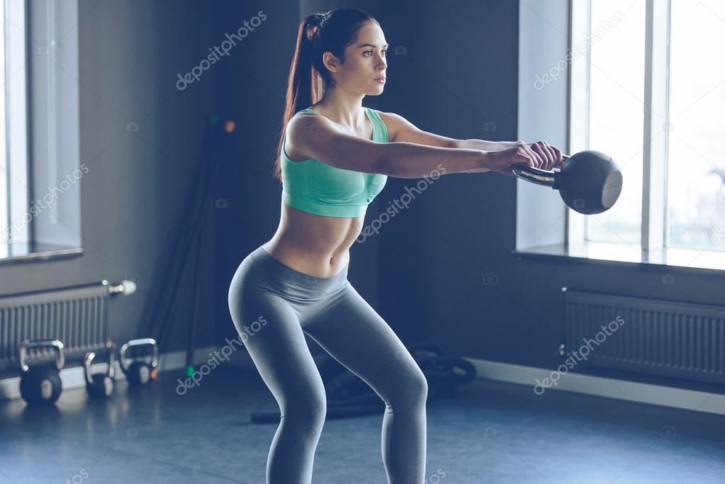 Beautiful woman working out with kettle bell at gym 