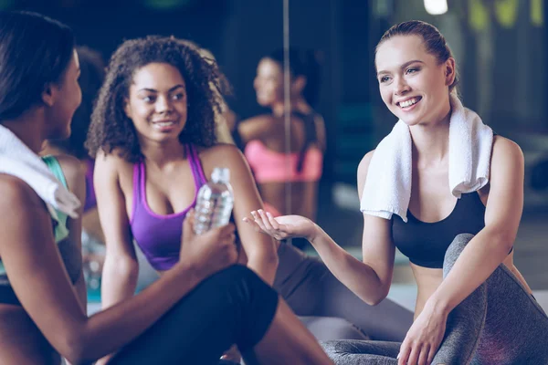 Lindas mulheres jovens sentadas no tapete de exercício — Fotografia de Stock