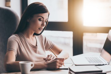 young beautiful woman writing in notebook 