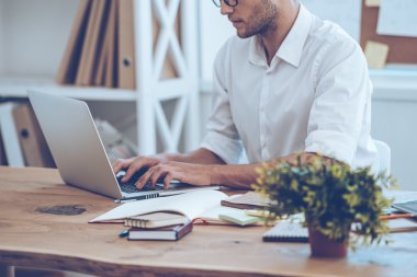 young man in glasses working with laptop