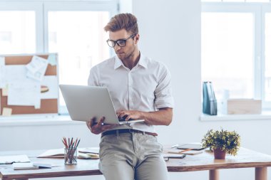 young man in glasses using his laptop