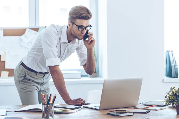 Man using his laptop and talking on phone — Stock Photo, Image