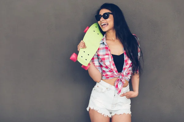 Beautiful young woman carrying skateboard — Stockfoto