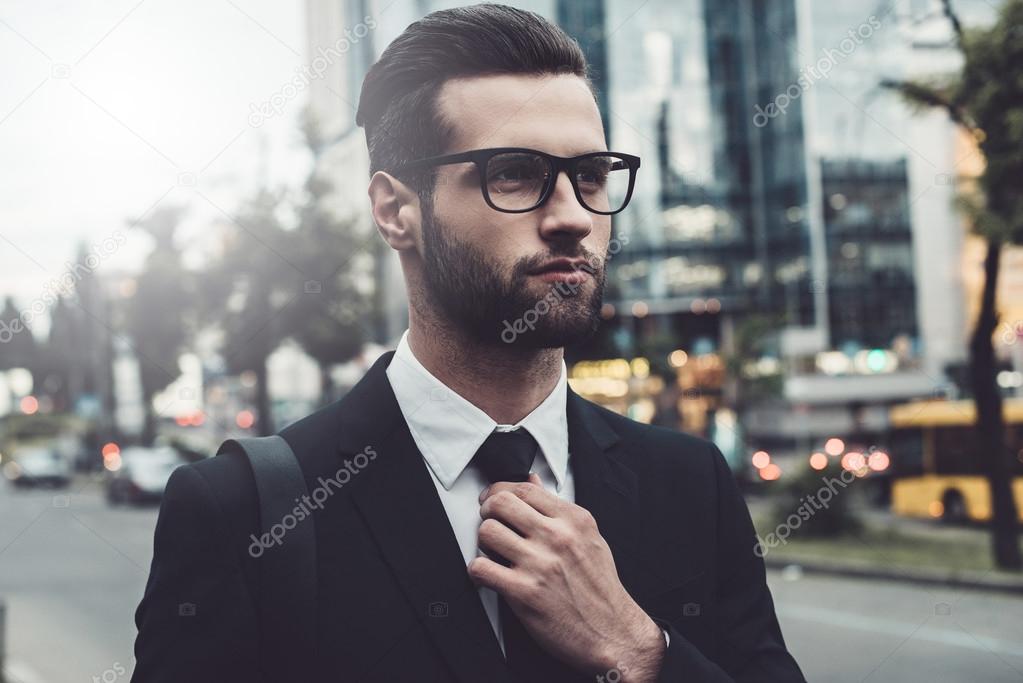 man in formalwear adjusting his necktie