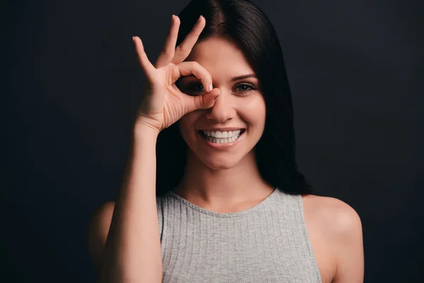 Frau gestikuliert mit Ok-Zeichen nahe ihrem Auge — Stockfoto