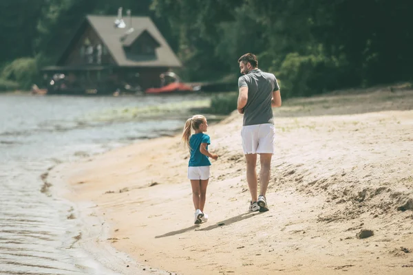 Padre e hija corriendo en la orilla del río — Foto de Stock