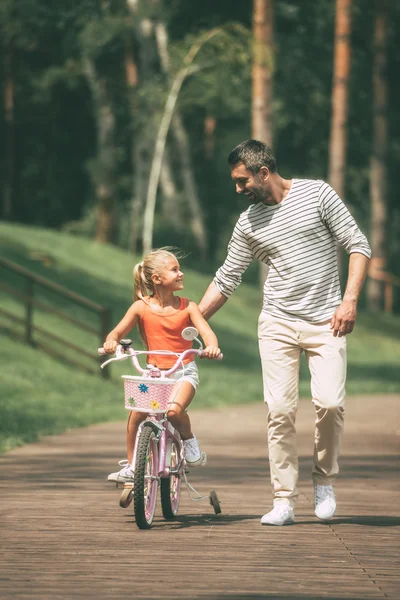 Father teaching his daughter to ride a bicycle — Stock Photo, Image
