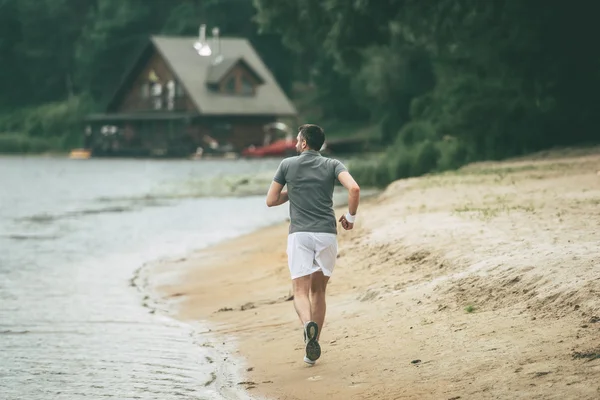 Homem correndo ao longo da margem do rio — Fotografia de Stock