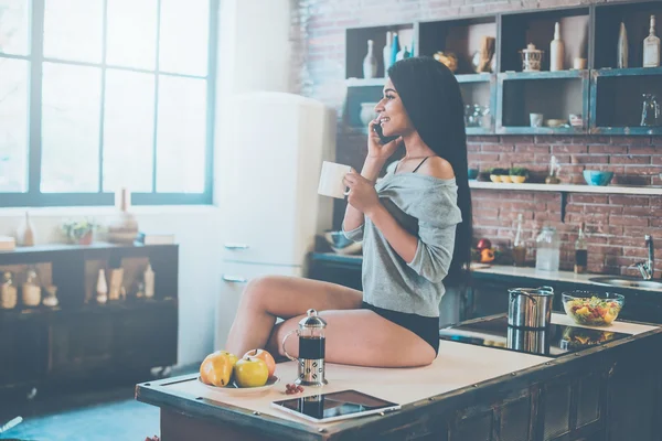 Женщина разговаривает по телефону на кухне — стоковое фото