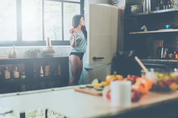 Женщина возле холодильника держит перец — стоковое фото
