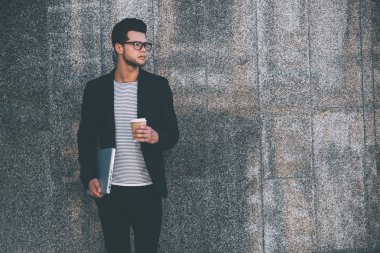 Dizüstü bilgisayar ve kahve taşıyan adam 