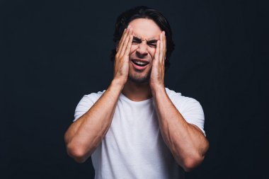 Yüzünü elleriyle kapatan adam.