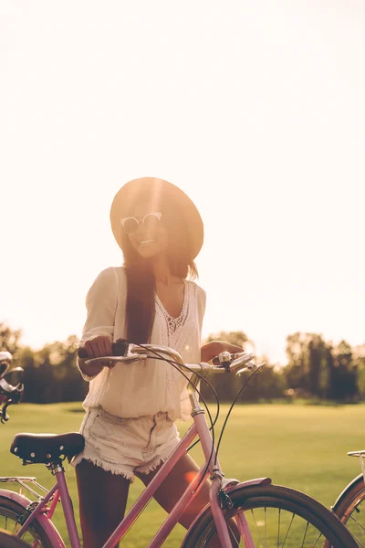 Jeune femme en fedora poussant son vélo — Photo