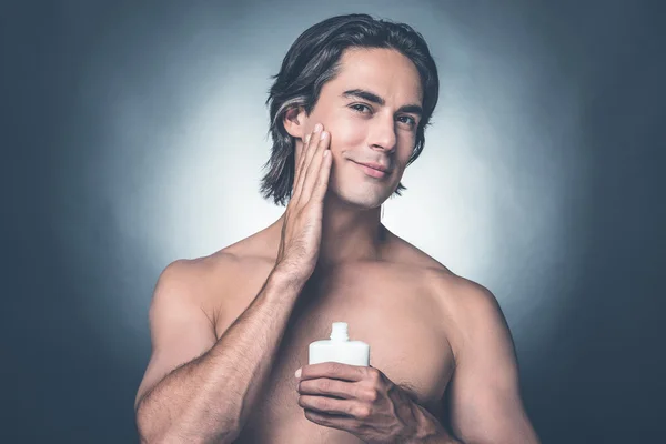 Hombre sin camisa aplicando loción aftershave — Foto de Stock