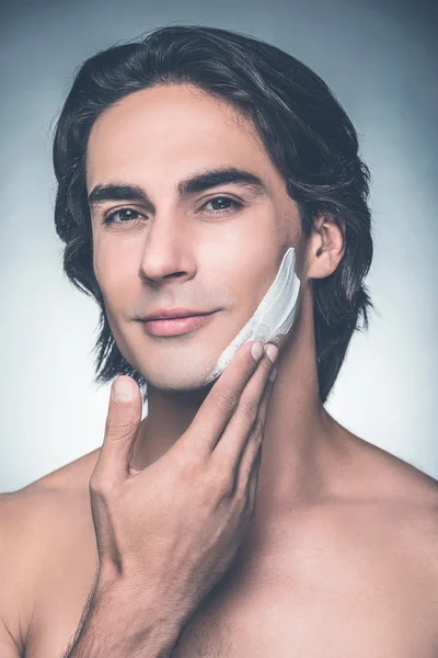 Young shirtless man applying cream — Stok fotoğraf