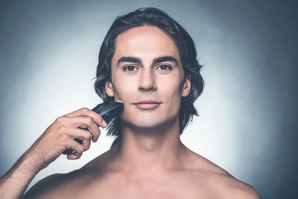 Shirtless man shaving with electric razor — Stock Photo, Image