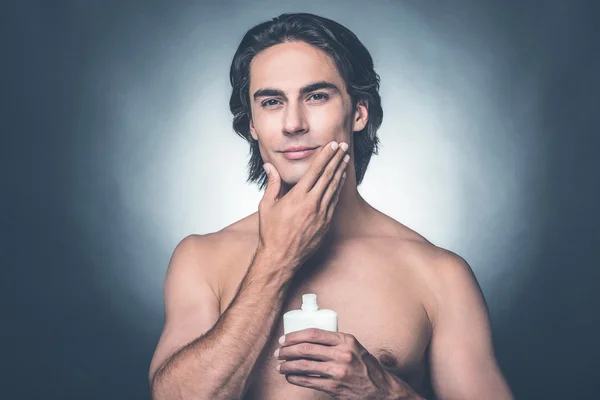 Homem sem camisa aplicando loção aftershave — Fotografia de Stock