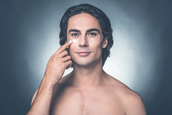 Young shirtless man applying moisturizer — Stock Photo, Image