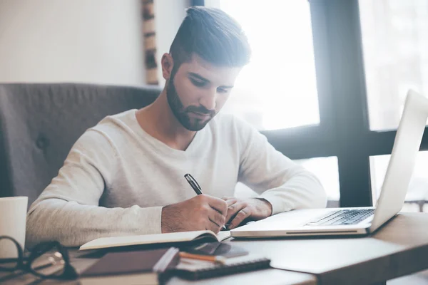 Young man writing notes in diary — Stock Photo, Image