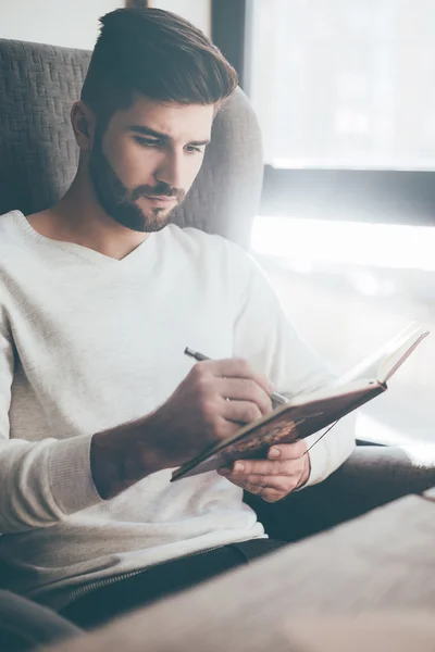 Jonge man schrijven nota's in dagboek — Stockfoto