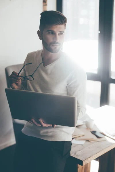 Hombre guapo sosteniendo portátil — Foto de Stock