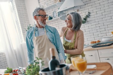 Joyful senior couple preparing to cook a dinner and smiling while spending time at home
