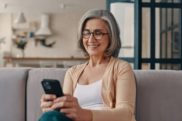 Beautiful Senior Woman Casual Clothing Using Her Smartphone While Sitting — Stockfoto