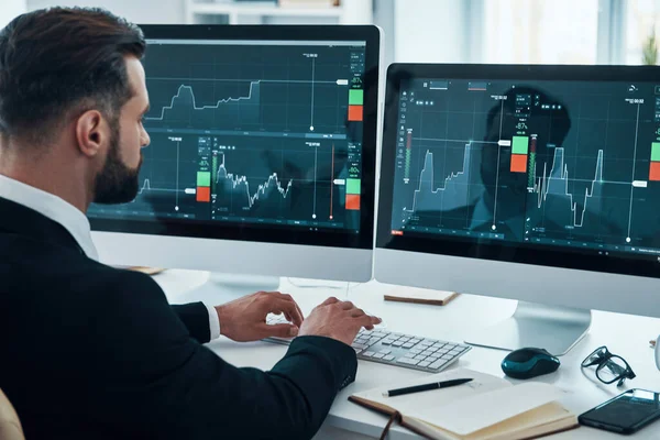 Konzentrierter junger Mann in Hemd und Krawatte bei der Analyse von Börsendaten im Büro — Stockfoto