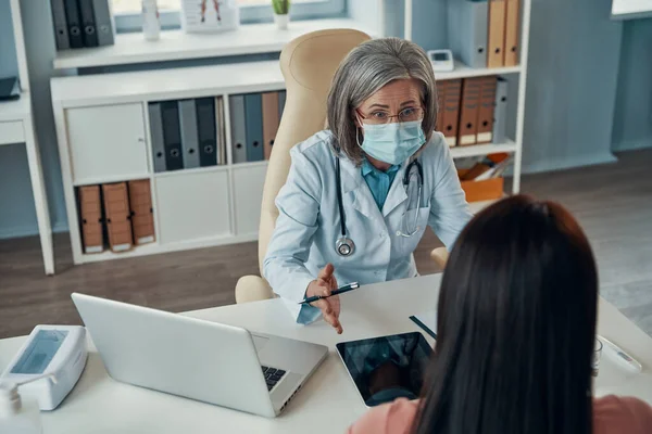 Top view of female doctor in white lab coat giving a healthcare consultation to young woman while sitting in her office — Stock Photo, Image