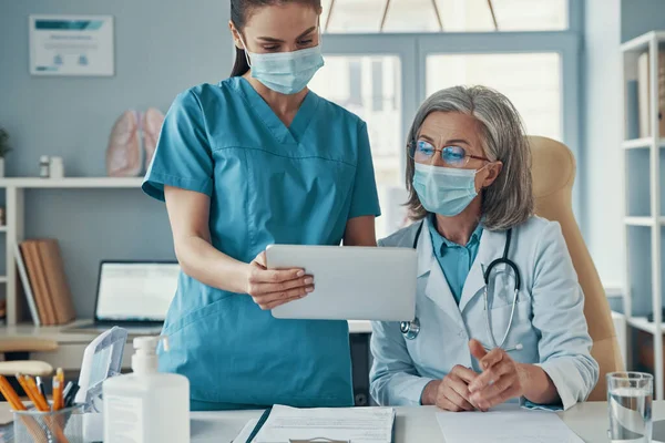 Dos compañeras de trabajo en uniforme médico y máscaras protectoras — Foto de Stock