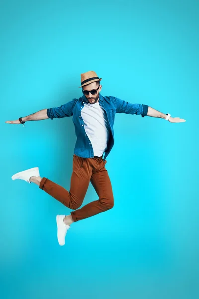 Full längd av stilig ung man som håller armarna utsträckta medan svävar mot blå bakgrund — Stockfoto